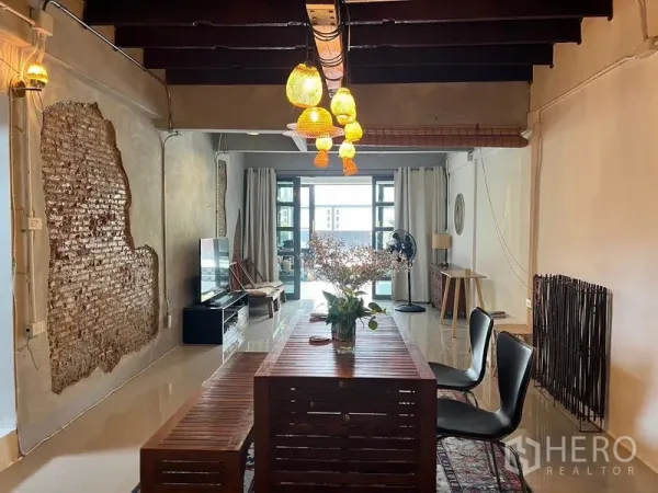 Townhouse for rent in Ratchathewi, Bangkok - Open-plan living and dining room with exposed brick, long wooden table and pendant lights.