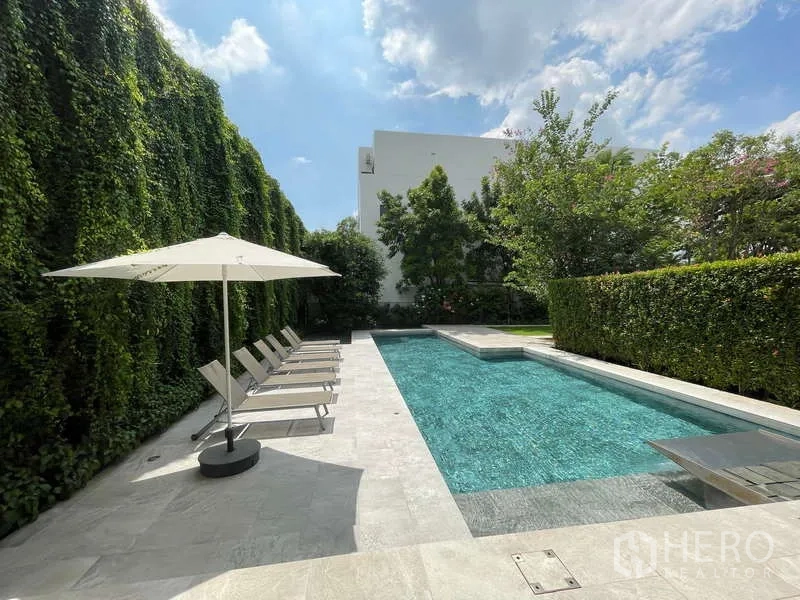 Home Office for rent in Don Mueang, Bangkok - Outdoor lap pool with sun loungers, umbrella and tall privacy hedges.