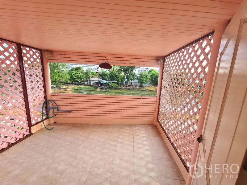 Detached House for rent in Sai Mai, Bangkok - Covered terrace with pink lattice panels overlooking a tranquil lakeside view.