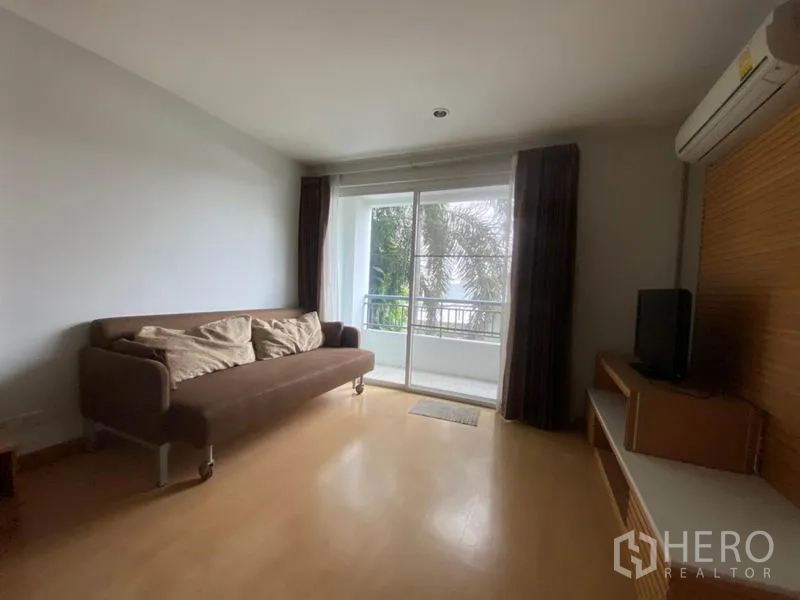 公寓 出租在Watthana, Bangkok - 起居区棕色沙发、电视柜，推拉门直达阳台。