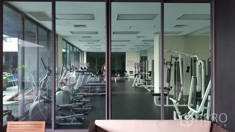 Condominium for rent in Khlong Toei, Bangkok - Condominium fitness center with cardio machines and weight equipment facing the pool area.
