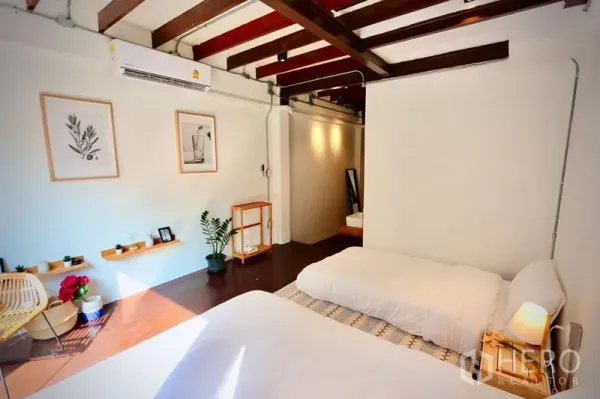 Office Space for rent in Sathon, Bangkok - Spacious bedroom with exposed beams, twin sleeping setup and minimalist decor.