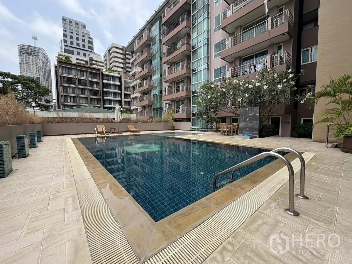 Condominium for rent in Khlong Toei, Bangkok - Poolside view with steps, deck chairs and condominium facade.