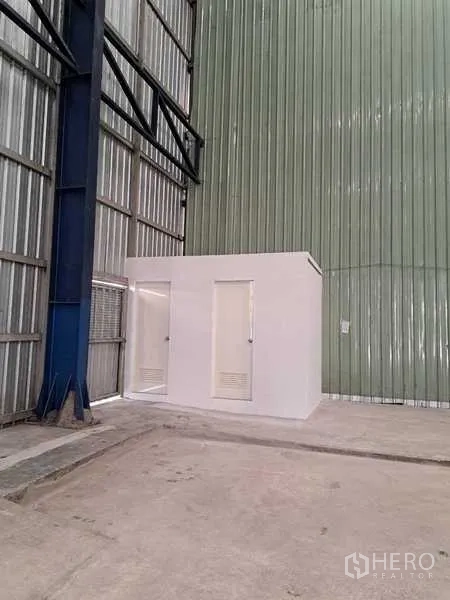 货栈 出租在Pak Kret, Nonthaburi - 仓库内白色独立卫生间单元，靠金属墙。