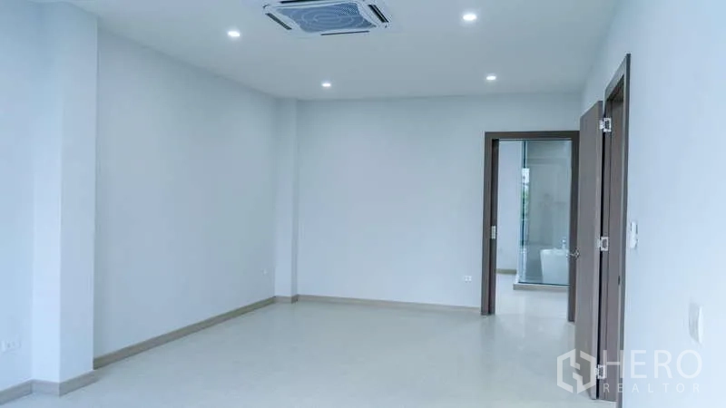 独立式住宅 出租或出售在Suan Luang, Bangkok - 明亮空旷的起居区，筒灯与嵌入式空调，白墙及通往浴室的门