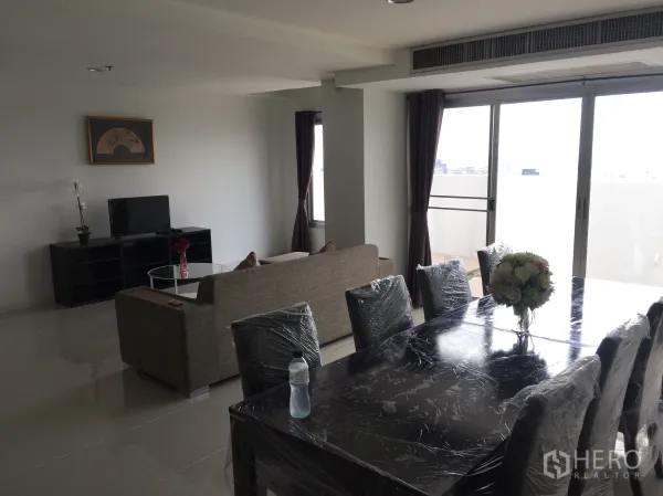 Condominium for rent in Khlong Toei, Bangkok - Bright living and dining room with sliding glass doors leading to a balcony.