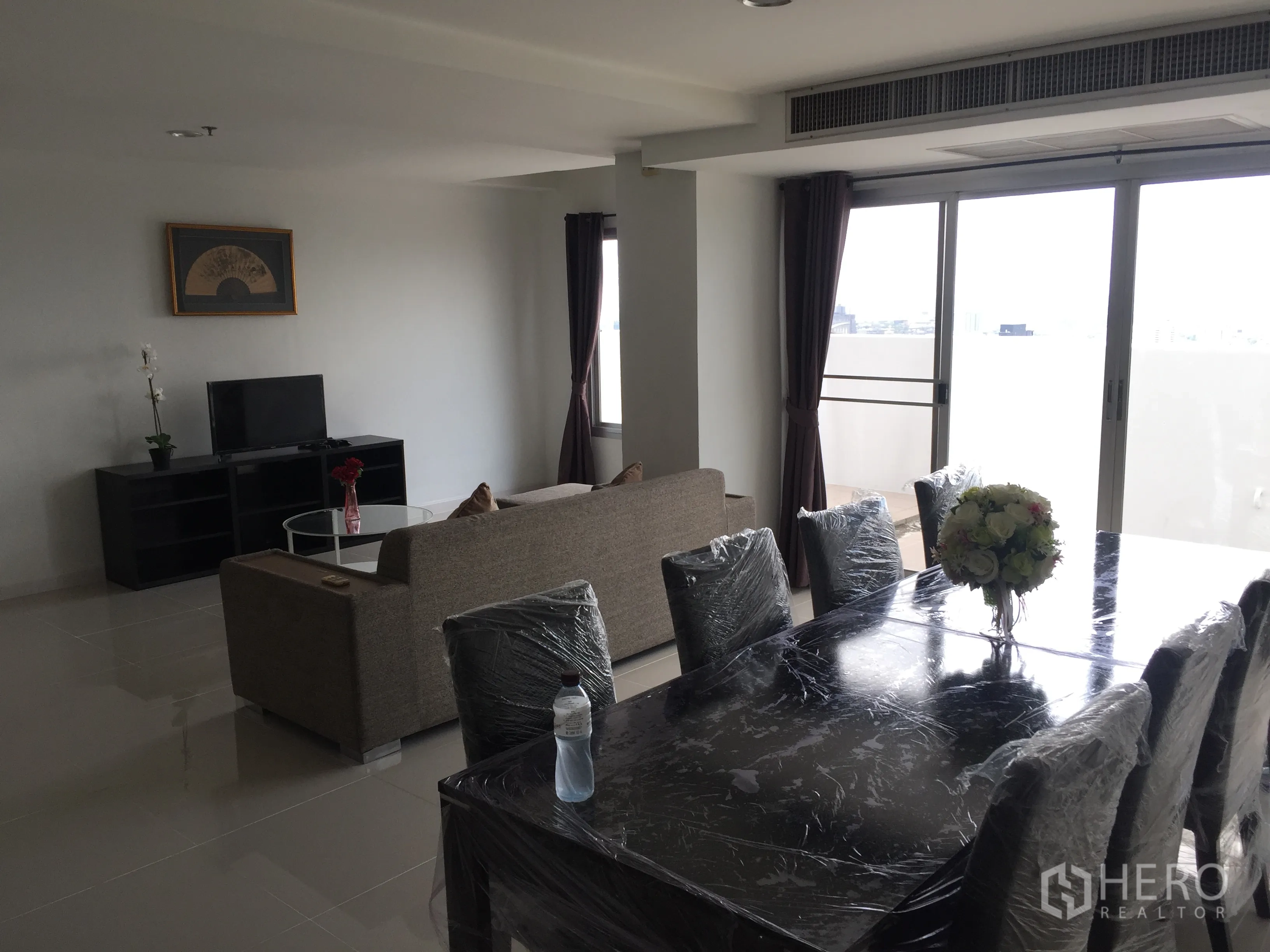 Condominium for rent in Khlong Toei, Bangkok - Bright living and dining room with sliding glass doors leading to a balcony.