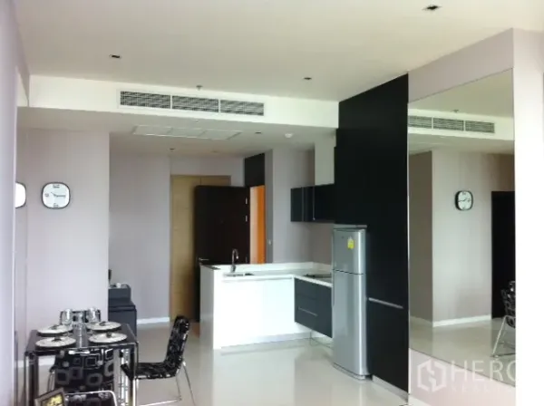 Condominium for rent in Watthana, Bangkok - Open-plan condo with white island kitchen, black cabinetry, dining set and mirrored wall.