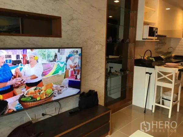 คอนโด ให้เช่าในWatthana, Bangkok - พื้นที่นั่งเล่นแบบโอเพ่นพร้อมทีวีติดผนัง เชื่อมครัวขนาดกะทัดรัดมีเคาน์เตอร์บาร์และชั้นกระจก