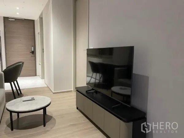 Condominium for rent in Khlong Toei, Bangkok - Minimalist living room with TV console, round coffee table and light wood floor