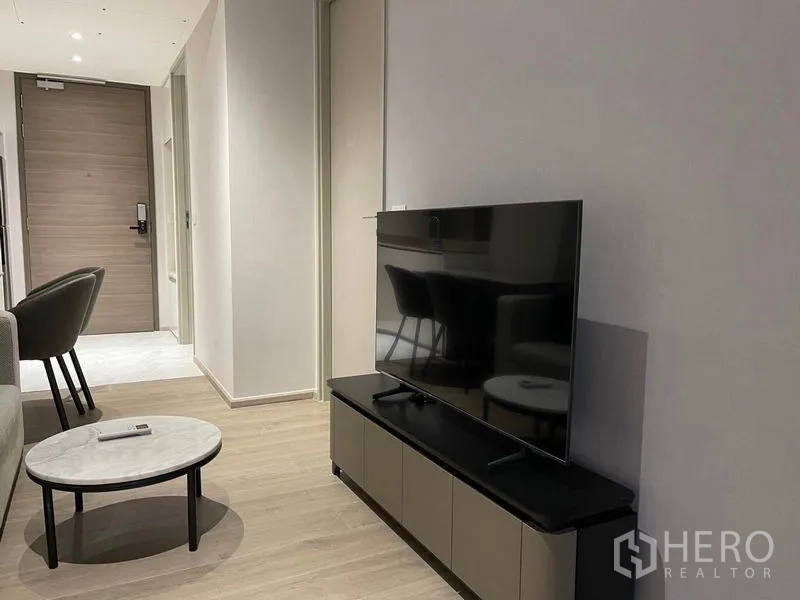 Condominium for rent in Khlong Toei, Bangkok - Minimalist living room with TV console, round coffee table and light wood floor