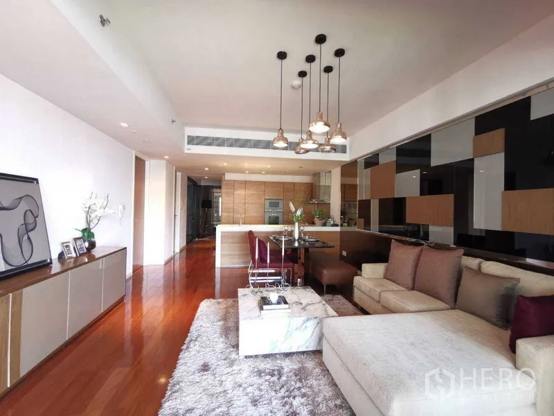 公寓 出租在Yan Nawa, Bangkok - 开放式客餐厅，转角沙发、大理石茶几、吊灯与现代厨房。
