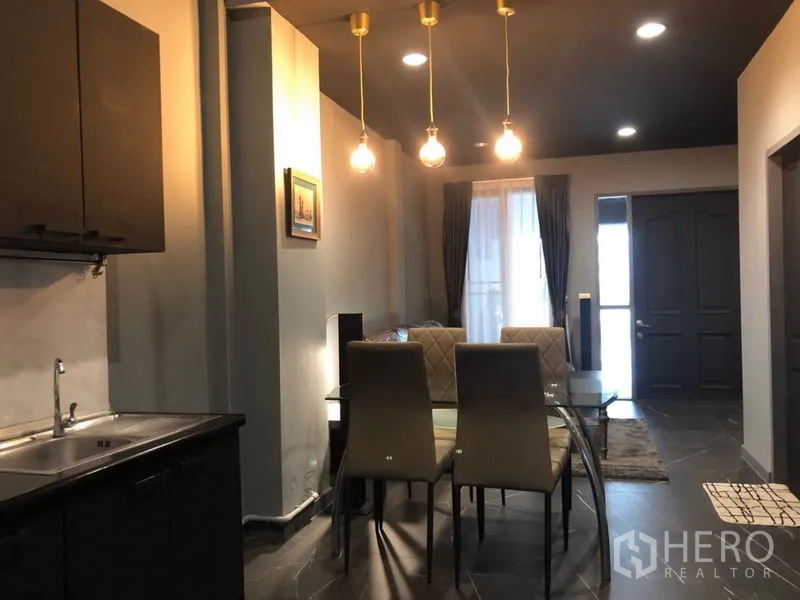 Townhouse for rent in Bang Kapi, Bangkok - Glass-top dining table for six under gold pendant lights facing the entrance.
