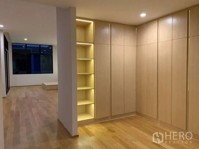Townhouse for rent or sale in Saphan Sung, Bangkok - Hallway to bedroom with illuminated display shelves and extensive wardrobes.