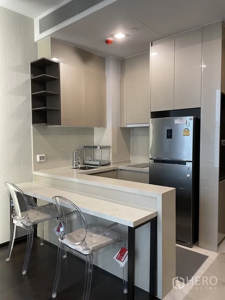 公寓 for rent in Watthana, Bangkok - 现代一字型厨房，亮面橱柜、吧台与不锈钢双门冰箱。