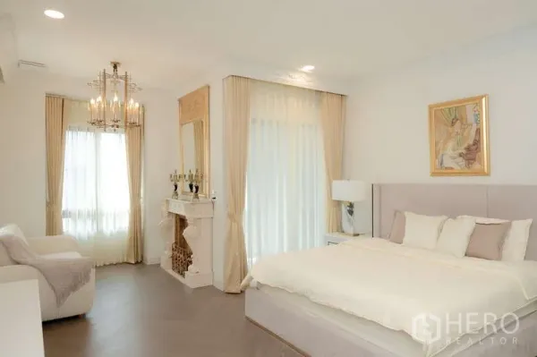 Detached House for rent or sale in Saphan Sung, Bangkok - Bright master bedroom with chandelier, decorative fireplace, large windows and an upholstered bed.