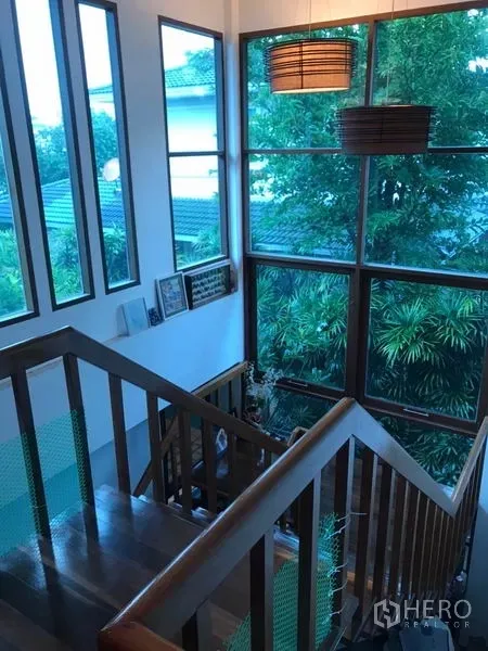 独立式住宅 出售在Lat Phrao, Bangkok - 楼梯平台设大面积转角窗，可眺望茂密绿景与周边屋顶。