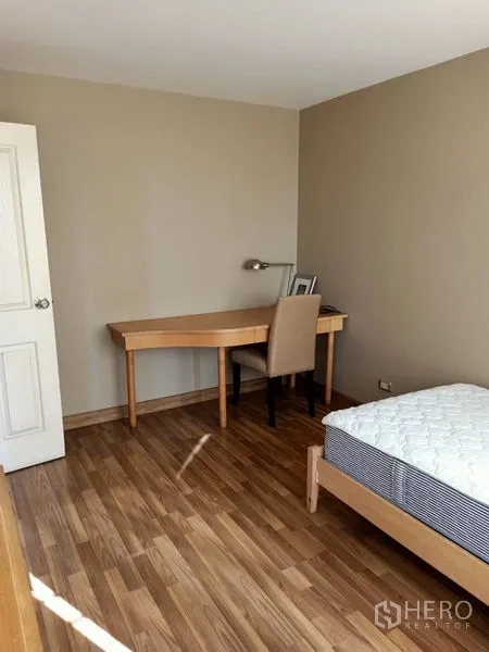 Condominium for rent in Khlong Toei, Bangkok - Second bedroom with single bed and a study desk on wood flooring.