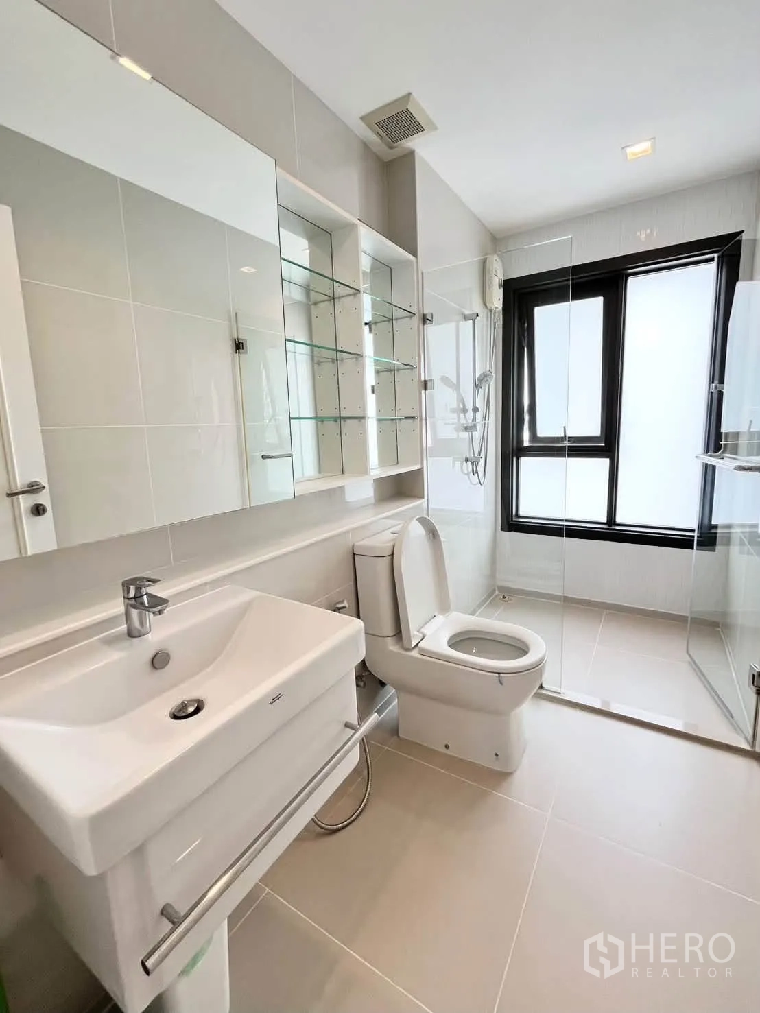 Condominium for rent in Pathum Wan, Bangkok - Clean bathroom with vanity, glass shelves, and a walk-in glass shower.
