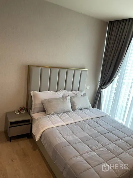 คอนโด ให้เช่าในWatthana, Bangkok - ห้องนอนหัวเตียงบุผ้า ชุดเครื่องนอนสีเทา พร้อมหน้าต่างสูงและผ้าม่านทึบ
