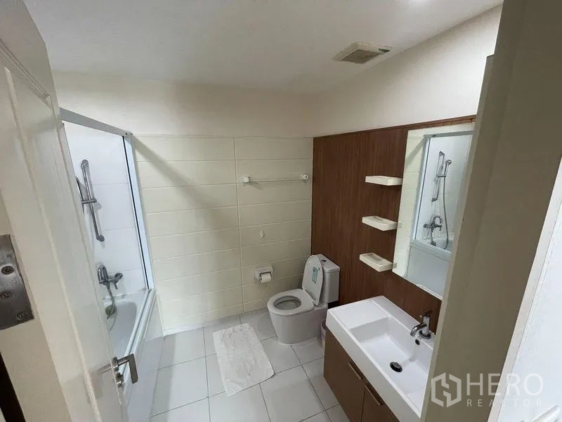 Condominium for sale - Bright bathroom with bathtub, toilet and modern vanity cabinet.
