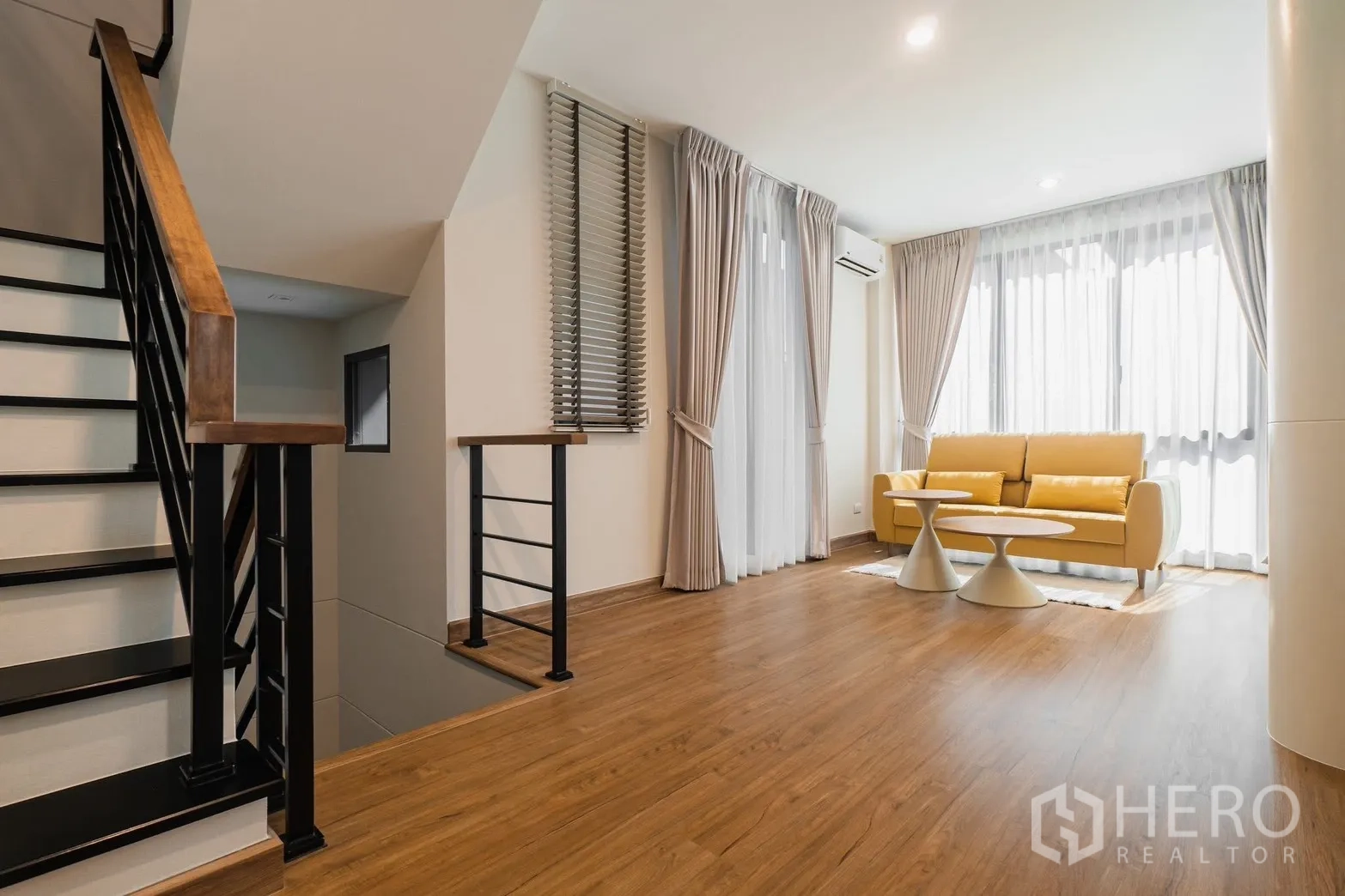 Detached House for rent or sale in Prawet, Bangkok - Stair landing family area with yellow sofa and warm wood floors
