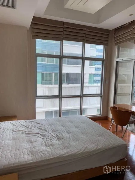 Condominium for rent in Pathum Wan, Bangkok - Bright bedroom with floor‑to‑ceiling windows, blackout blinds and balcony access.