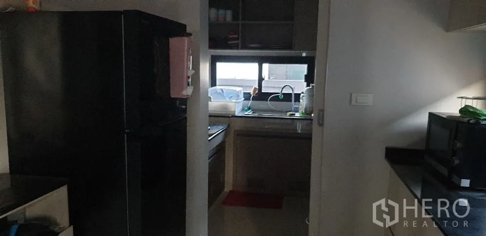 Detached House for rent or sale in Lam Luk Ka, Pathum Thani - Hallway view toward kitchen with double‑door fridge and built‑ins.