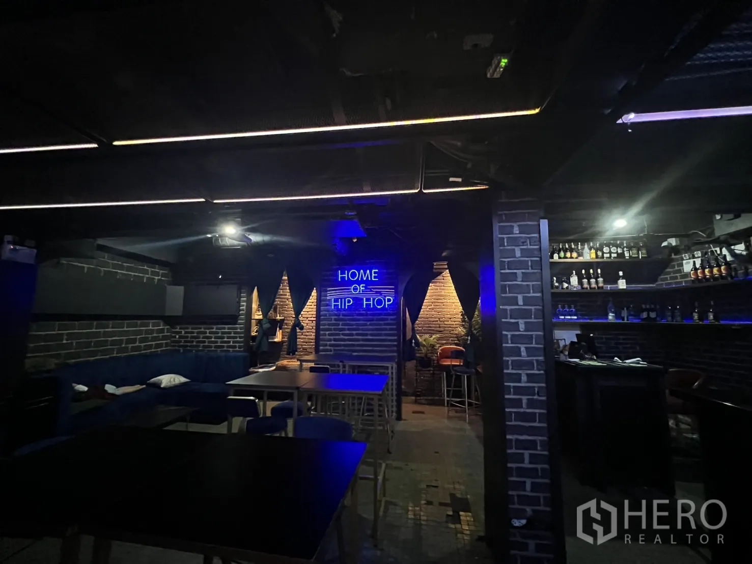 Retail Space for rent in Bangkok - Dining area with tables, banquette seating and neon sign.