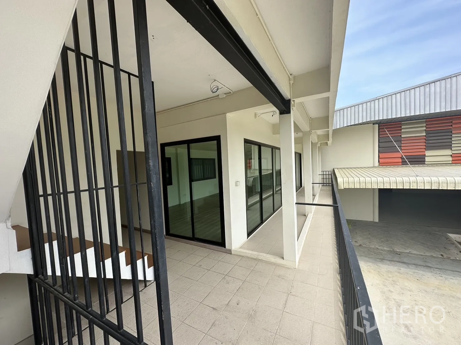 Warehouse for rent in Suan Luang, Bangkok - External corridor with metal railings and sliding glass doors connecting offices.
