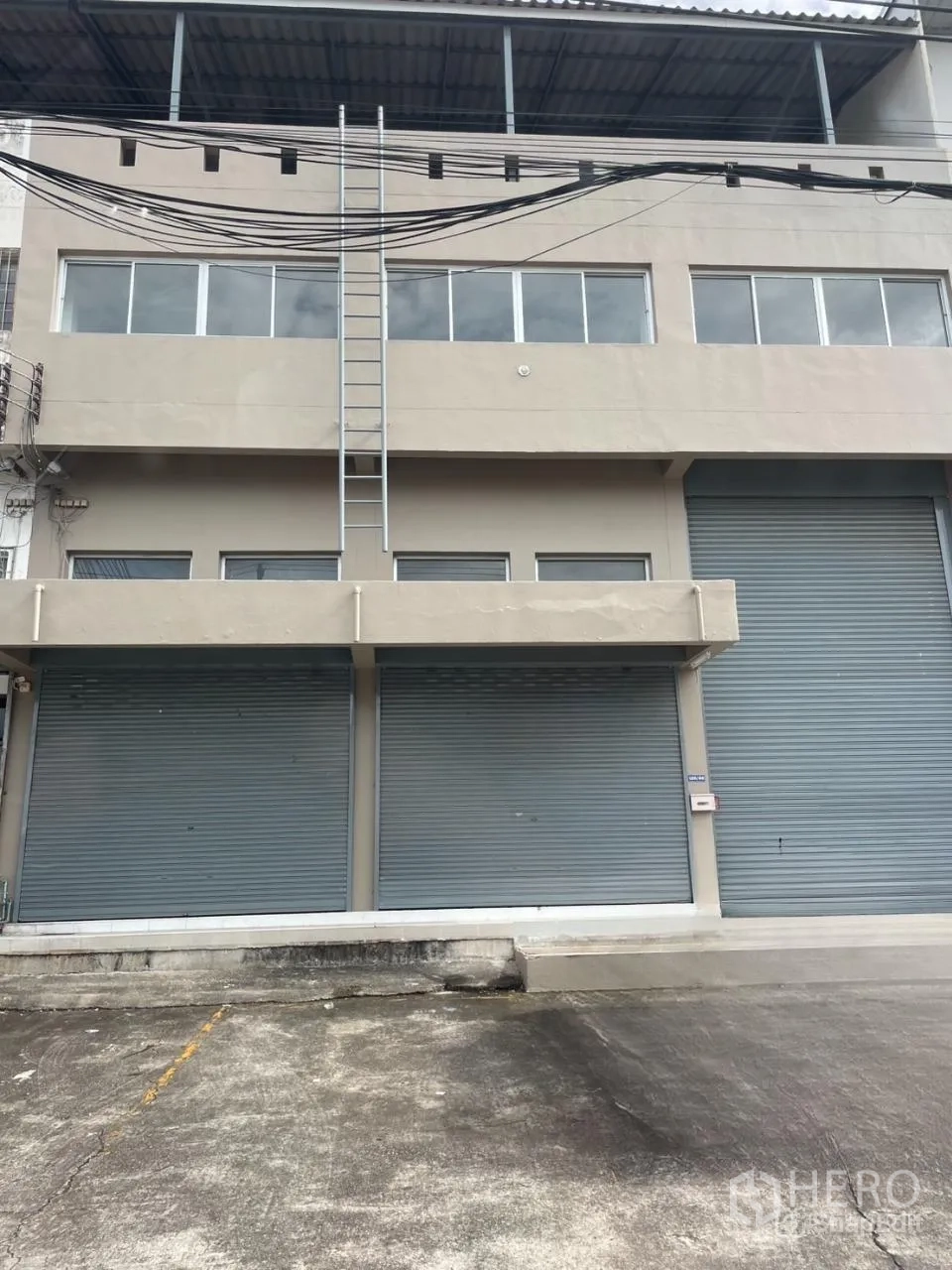 货栈 出租在Bang Phli, Samut Prakan - 北榄府邦普里仓库外立面，临街多卷闸门、装卸前场与顶部遮棚