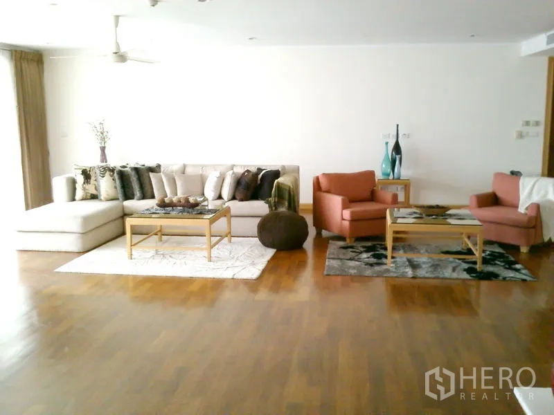 Condominium for rent in Khlong Toei, Bangkok - Expansive living room with sectional sofa, armchairs and coffee tables.