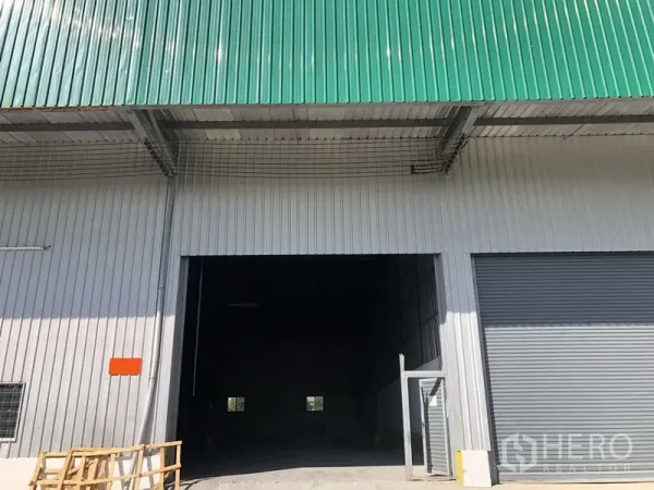 Warehouse for rent in Lat Krabang, Bangkok - Warehouse exterior with green metal roof, large roller shutter door and wide loading entrance in Lat Krabang, Bangkok.