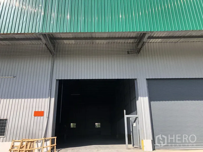 Warehouse for rent in Lat Krabang, Bangkok - Warehouse exterior with green metal roof, large roller shutter door and wide loading entrance in Lat Krabang, Bangkok.