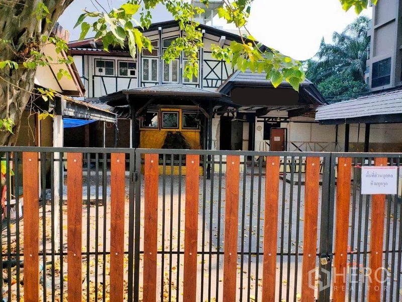 พื้นที่ขายปลีก ให้เช่าในKhlong Toei, Bangkok - อาคารพื้นที่ค้าปลีกสไตล์ทิวดอร์ พร้อมรั้วหน้าบ้าน ลานกว้าง ใต้ต้นไม้ใหญ่ และทางเข้าแบบมีหลังคา ในย่านเมือง