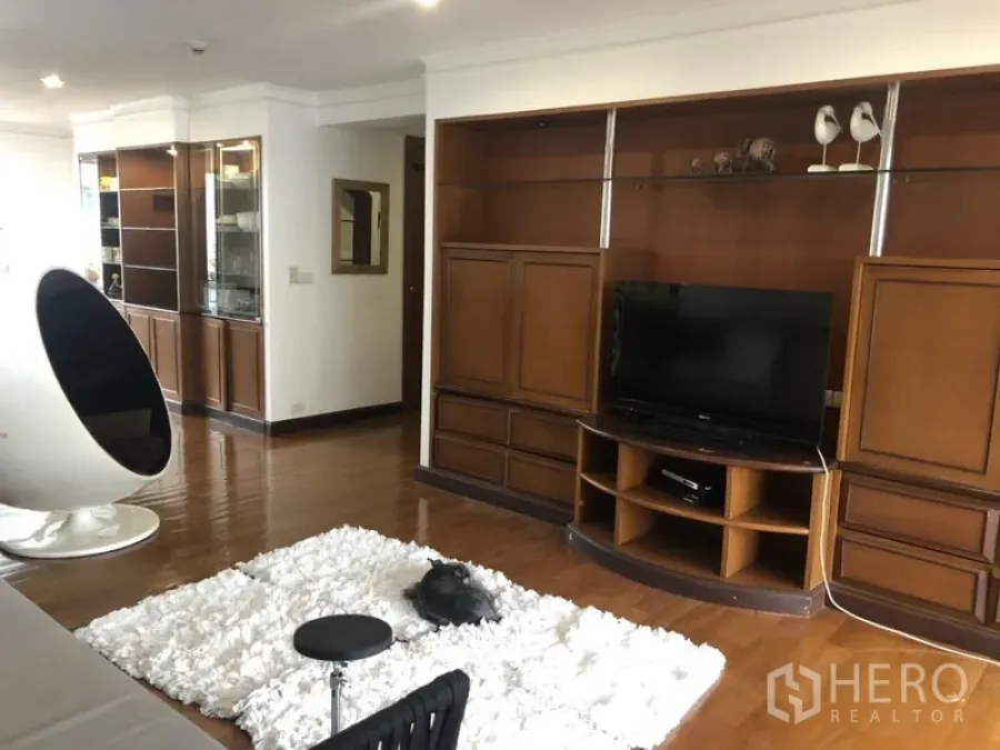 Condominium for sale in Watthana, Bangkok - Living room with wall-to-wall built-in TV cabinet and glossy hardwood floors.