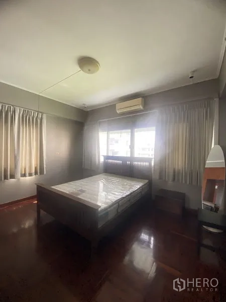 公寓 出租在Sathon, Bangkok - 次卧配床与分体式空调，双窗与深色木地板。