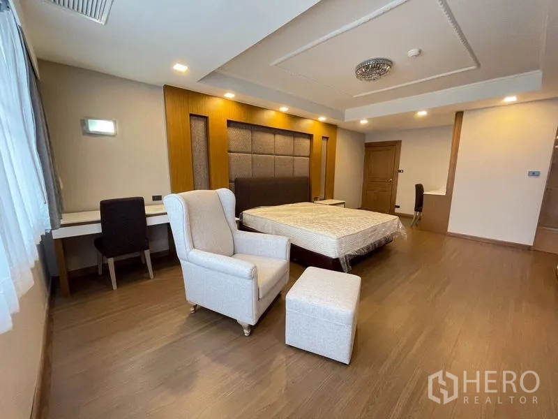 公寓 出租在Watthana, Bangkok - 卧室一角，扶手椅配脚凳、书桌与柔和灯光。