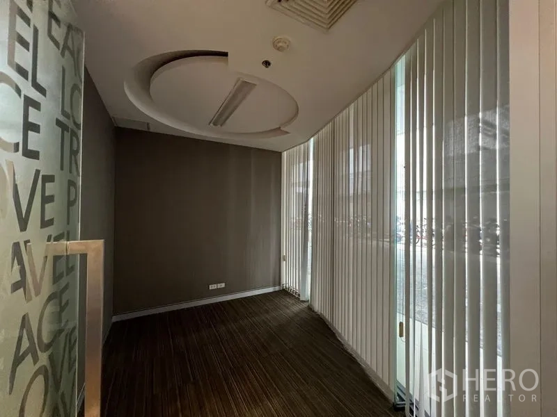 Retail Space for rent - Narrow retail entry room with floor-to-ceiling glass, vertical blinds and a circular recessed ceiling feature.