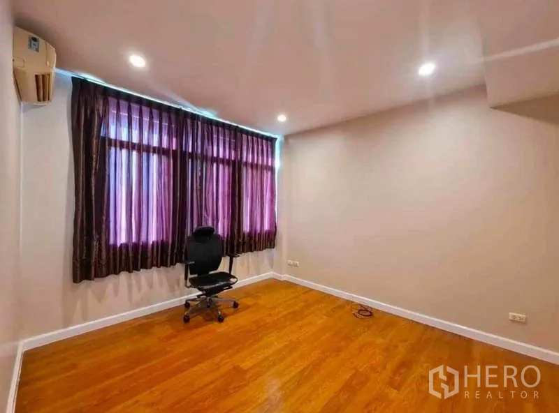 Townhouse for rent in Phra Khanong, Bangkok - Multipurpose room with wood floor, ceiling lights and dark curtains with an office chair.