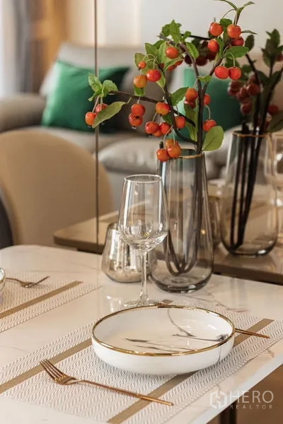Condominium for rent in Khlong Toei, Bangkok - Elegant table setting with vase, glassware, and plate on a light dining table.