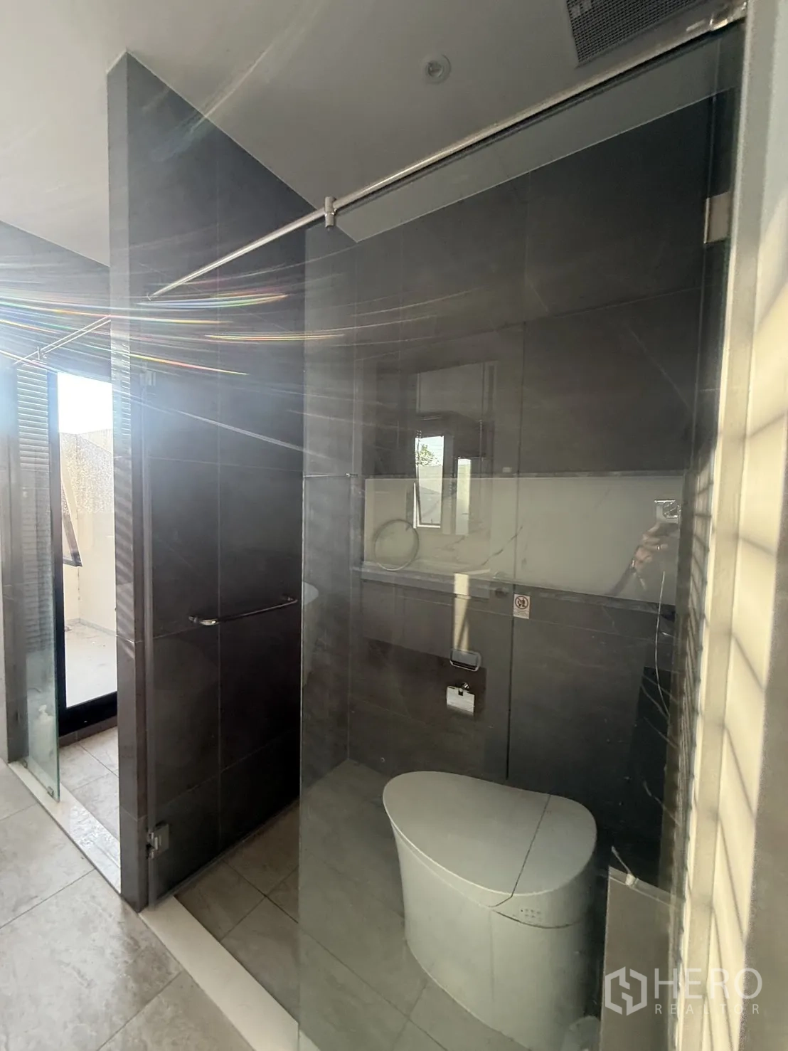 Detached House for rent in Saphan Sung, Bangkok - Dark-tiled bathroom with glass shower enclosure and modern toilet.
