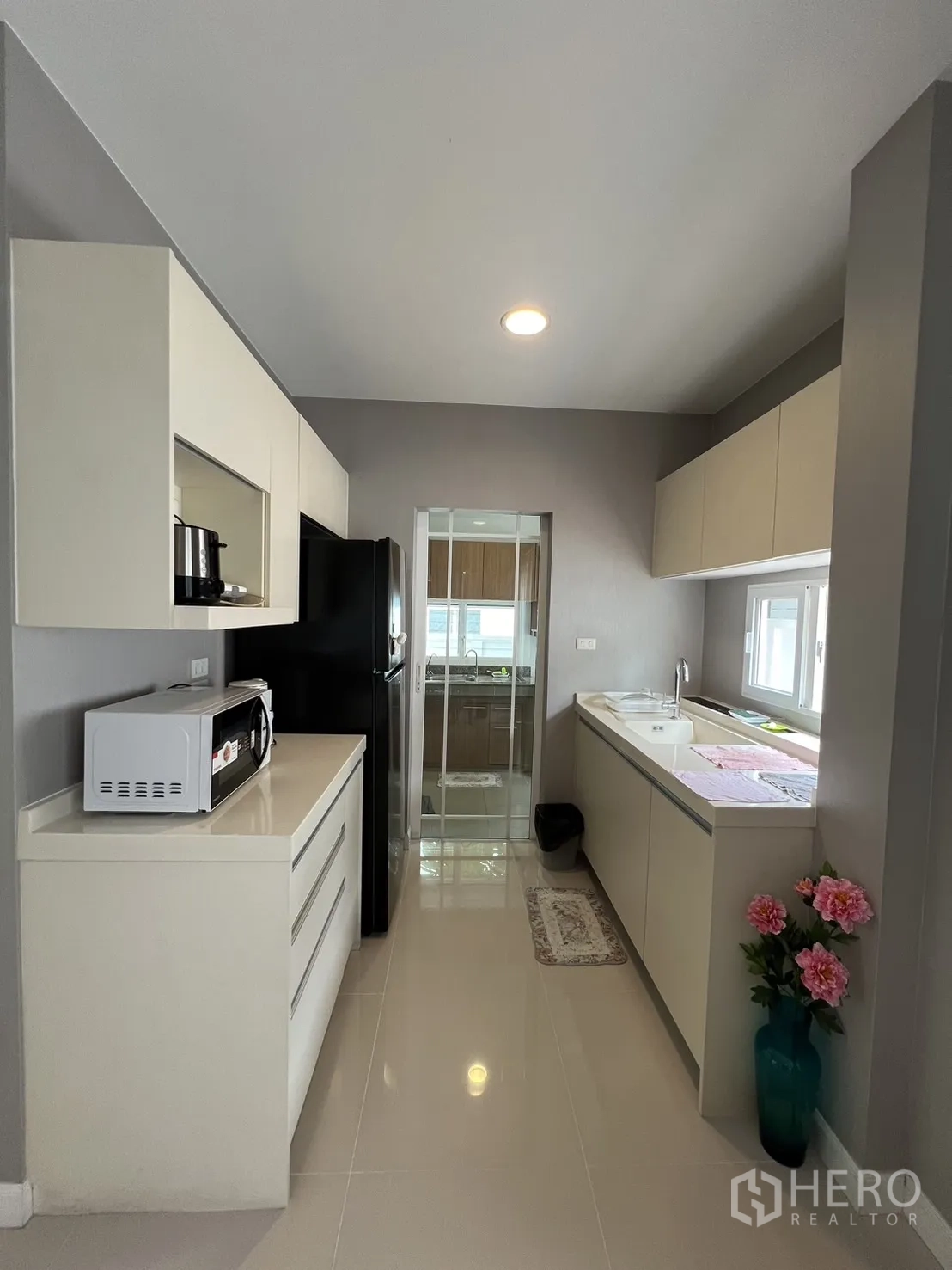 Detached House for rent in Bang Kapi, Bangkok - Compact pantry kitchen with cabinets leading to an enclosed Thai kitchen.