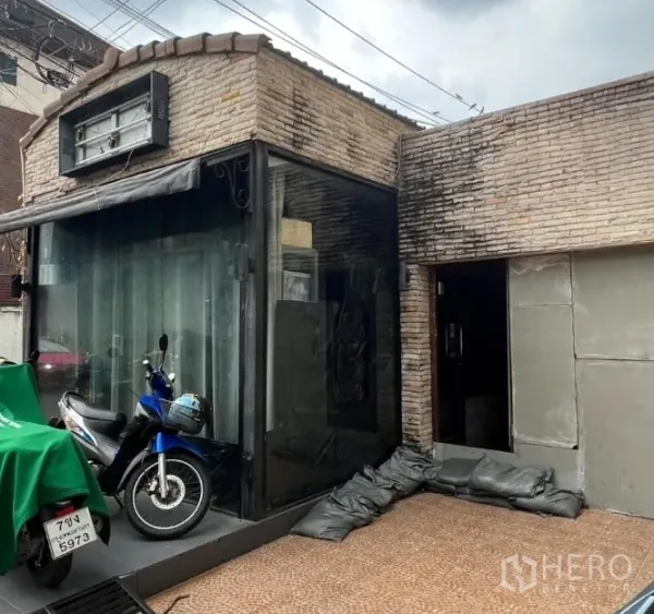 Retail Space for rent in Watthana, Bangkok - Corner glass display and entrance of brick shop space with canopy and signage frame.