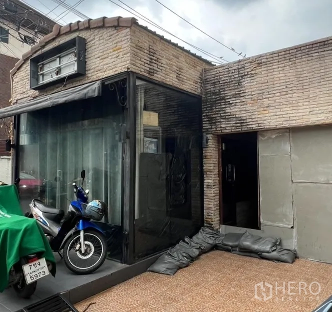 Retail Space for rent in Watthana, Bangkok - Corner glass display and entrance of brick shop space with canopy and signage frame.