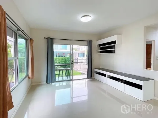 บ้าน ให้เช่าในBang Na, Bangkok - ห้องนั่งเล่นสว่างมีประตูกระจกบานเลื่อนออกสู่เฉลียงและตู้ทีวีบิลท์อิน