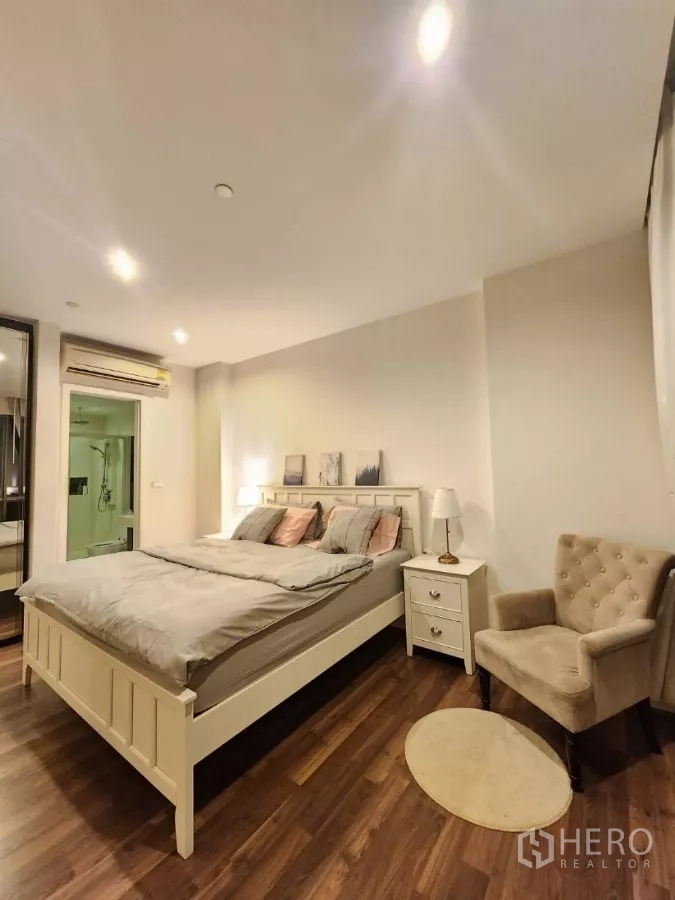 Condominium for rent in Phra Khanong, Bangkok - Master bedroom with upholstered chair and view to the ensuite entrance.