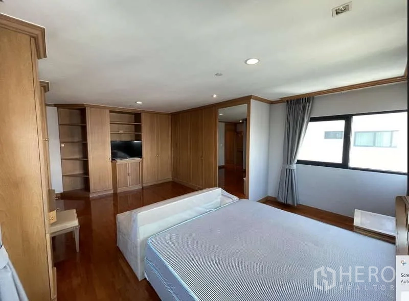 Condominium for rent - Bedroom angle showing built-in shelves, TV cabinet and extensive wardrobes.