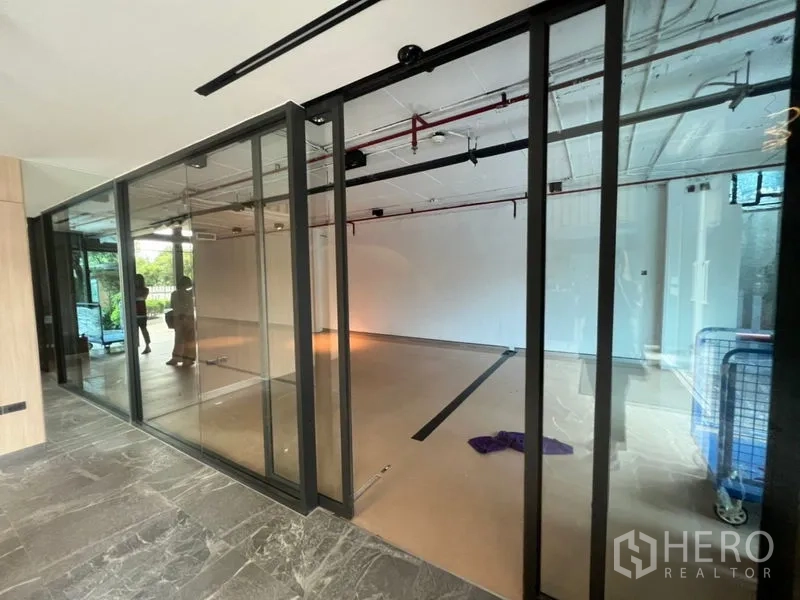 办公空间 出租在Watthana, Bangkok - 带滑动玻璃隔断的现代办公角落，工业风天花。