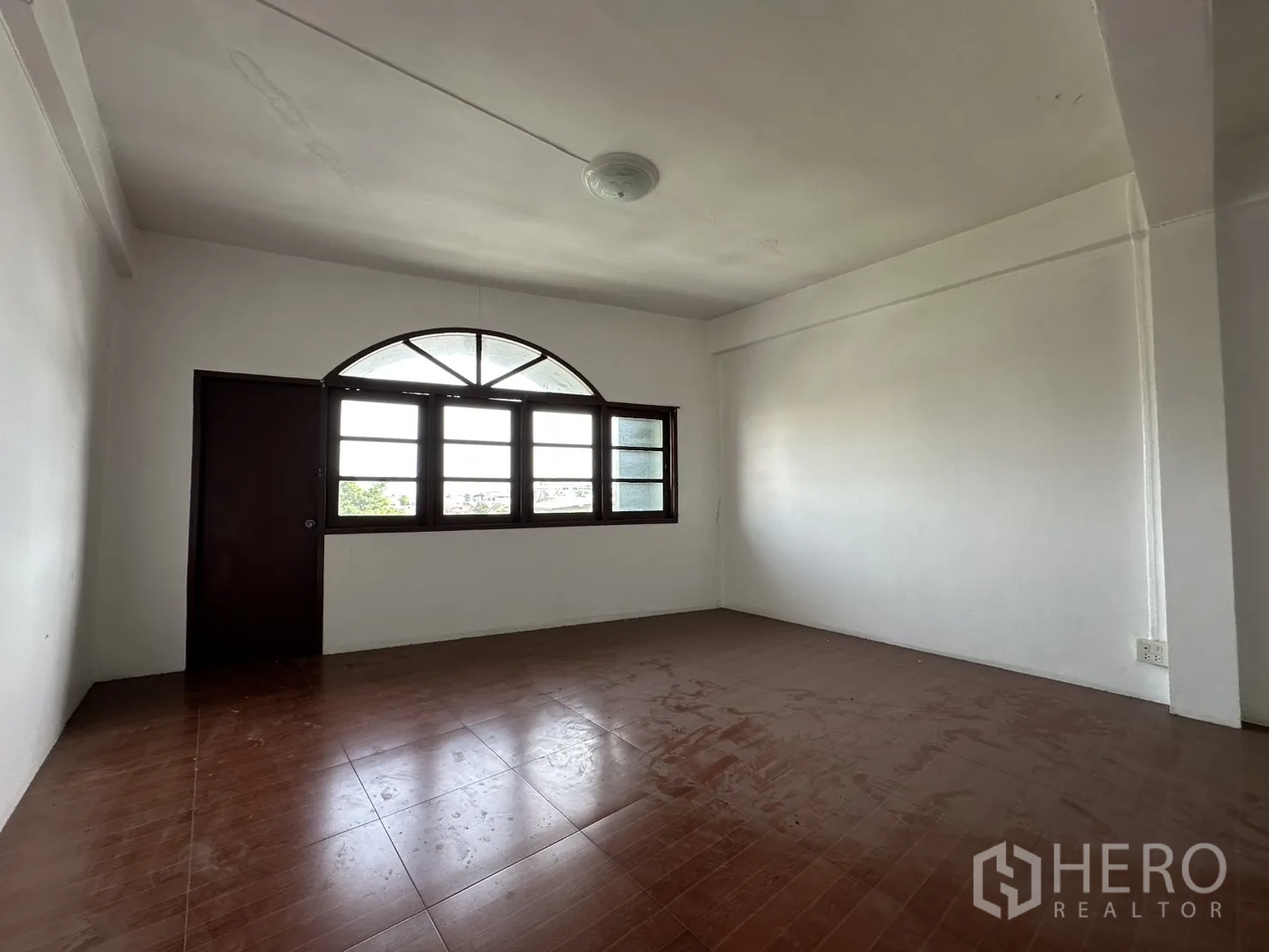 Shophouse for rent in Phra Khanong, Bangkok - Spacious room with arched window on the upper floor.